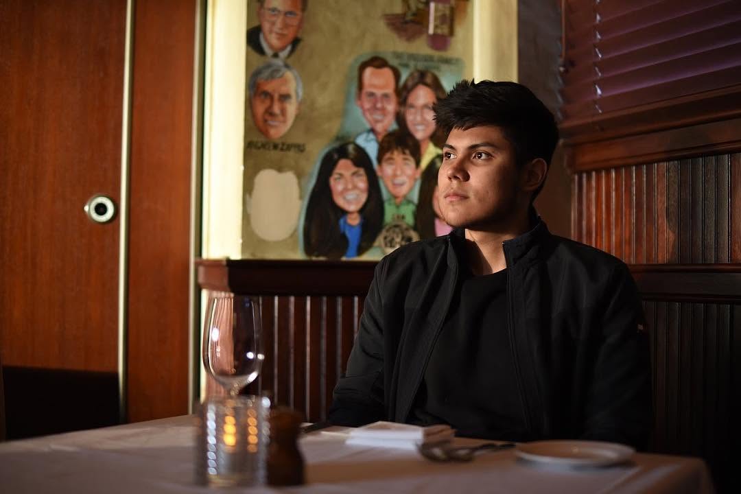 Still from a film Steven directed, edited and acted in: Steven seated in a dimly lit restaurant booth