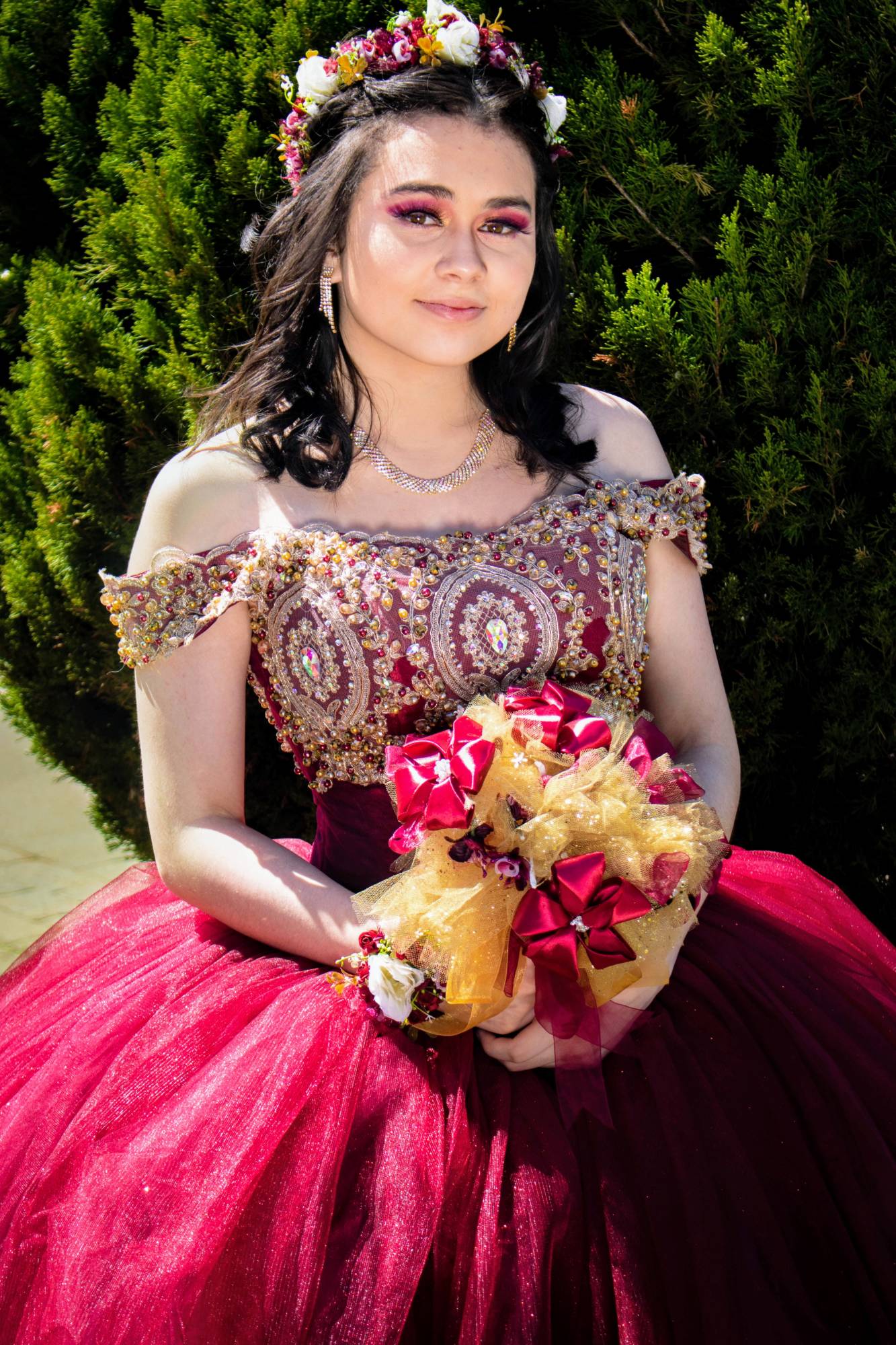 Quinceañera portrait in a burgundy gown with a bouquet, by @stevfilmstudios