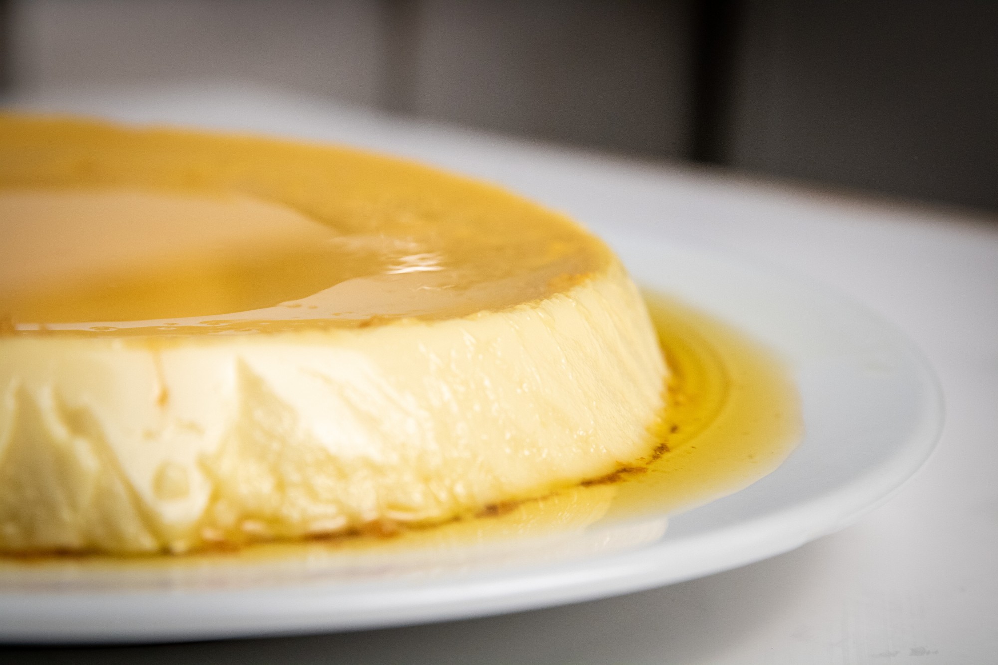 Close-up of caramel flan on a white plate, by @stevfilmstudios